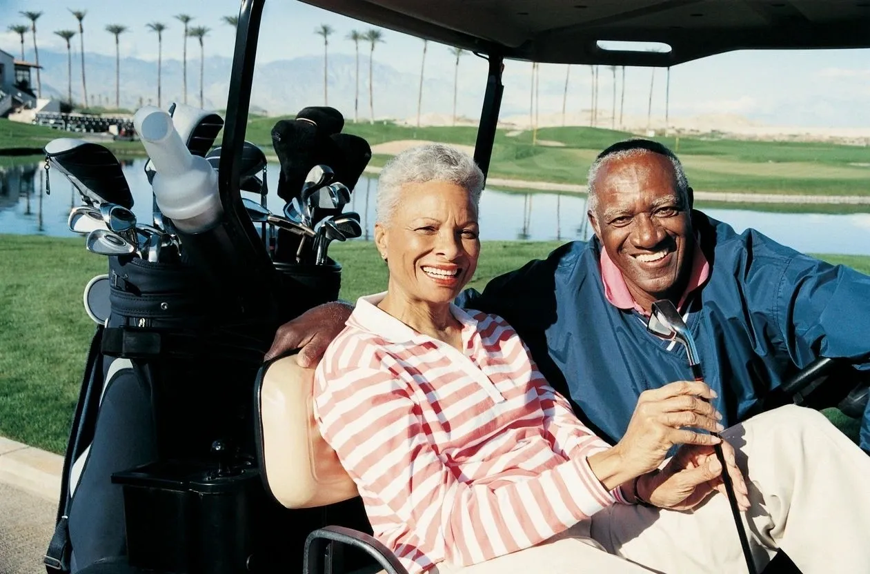 A man and woman sitting in the back of a golf cart.